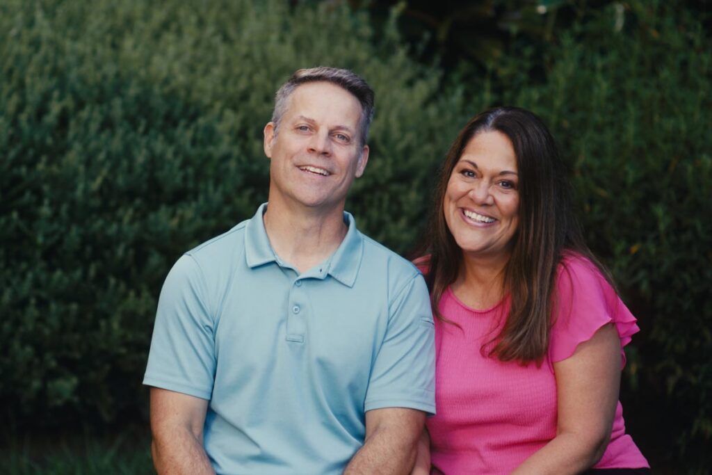 Mike and Lori lean gently towards each other and smile at the camera