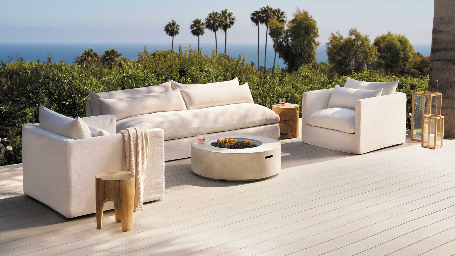 White couch set and fire pit on a light tan deck