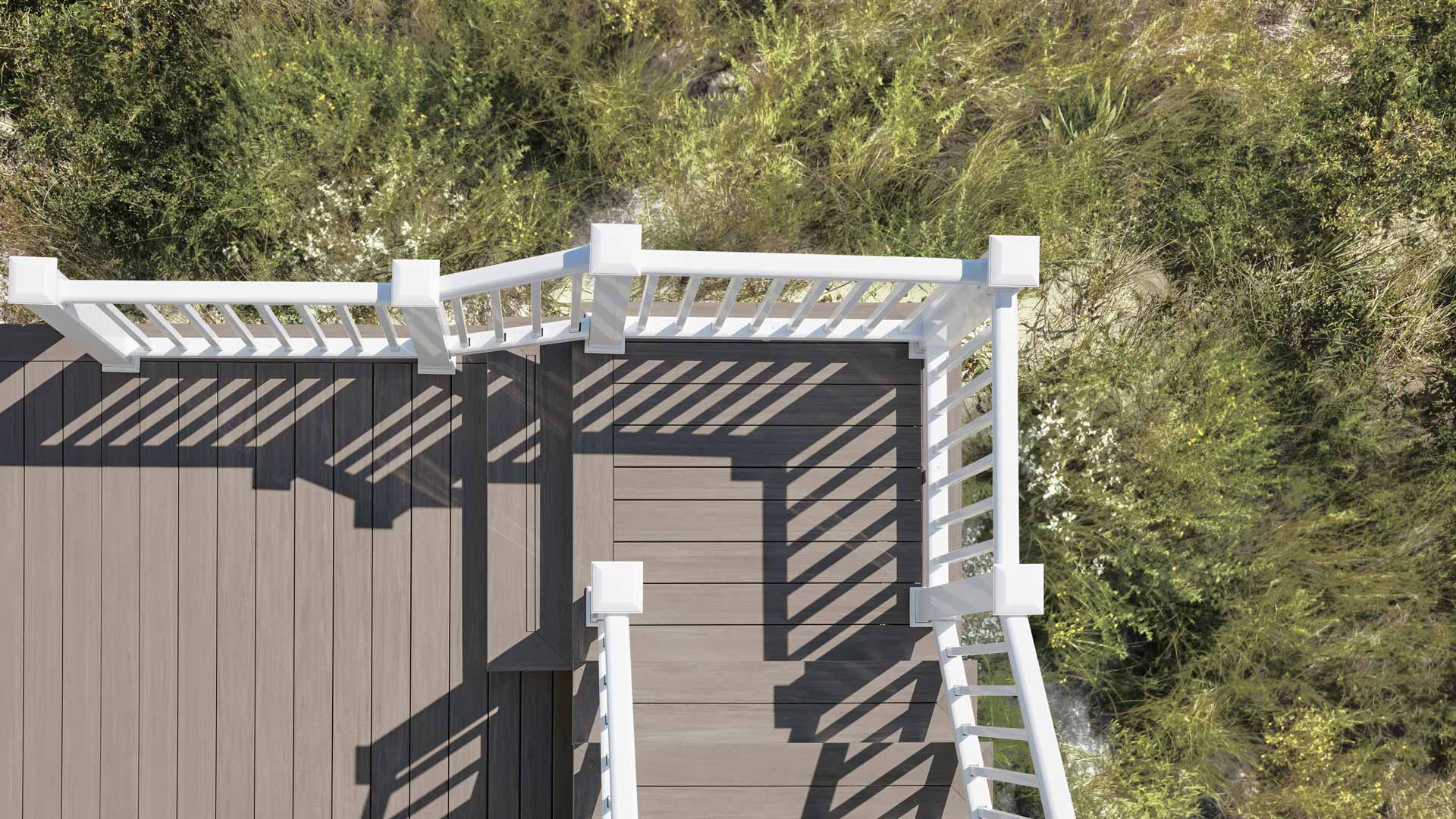 Aerial view of a TimberTech Advanced PVC deck in Coastline with a white railing with wild bushes growing below
