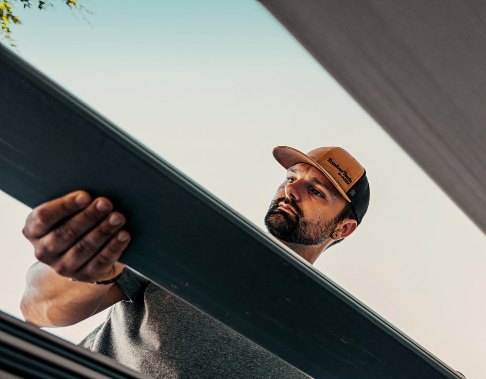 A TimberTech pro holds a deck board during a deck installation