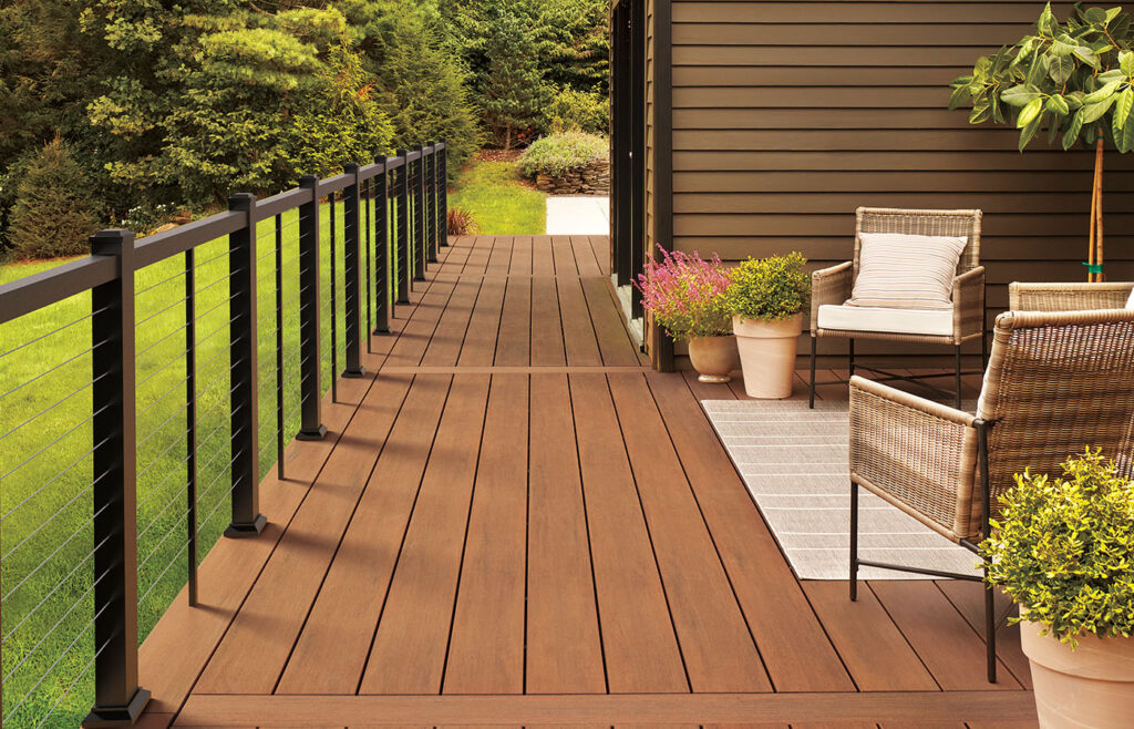 Relaxing outdoor space with wooden deck, chairs, and lush green plants.