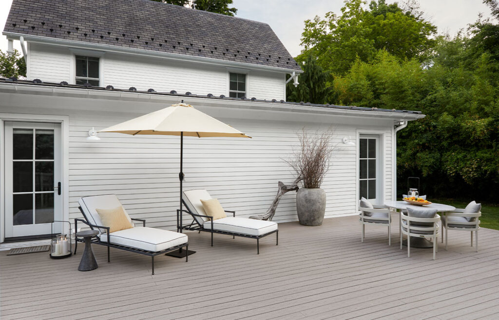 White siding with patio chairs and pillows on a slate gray decking from the Harvest Collection.