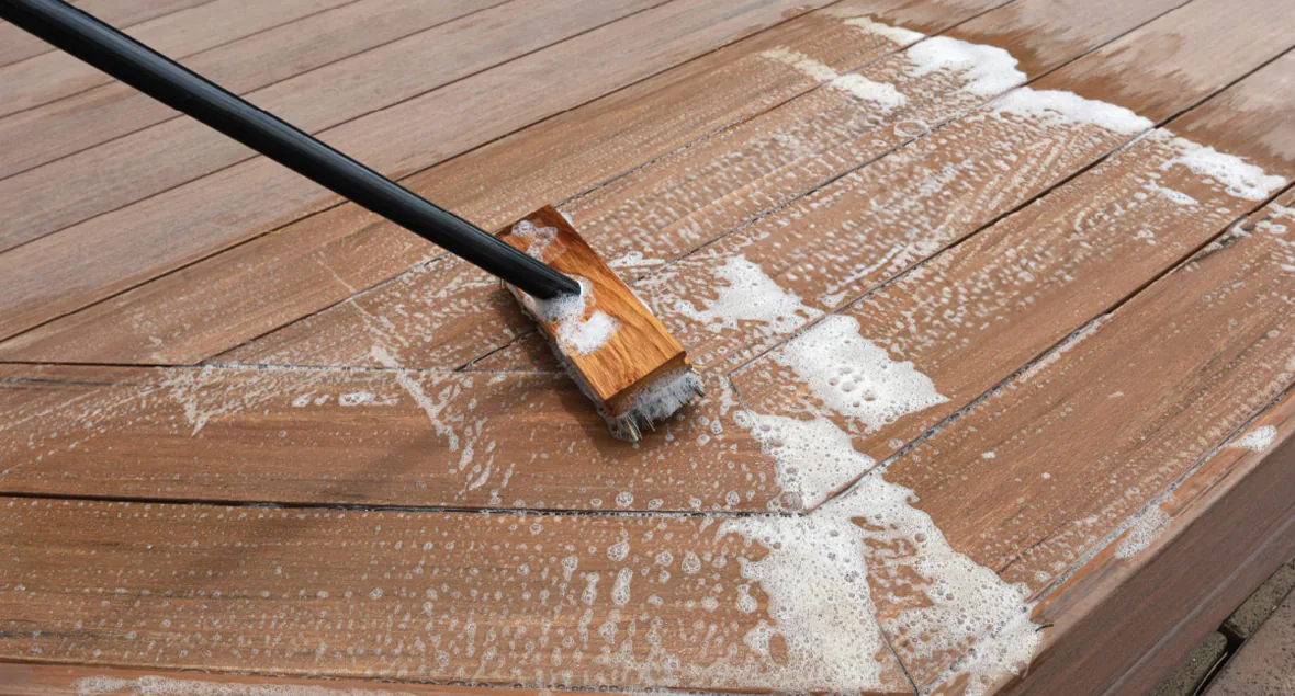 A soapy deck brush scrubs with the grain to clean the deck's surface.