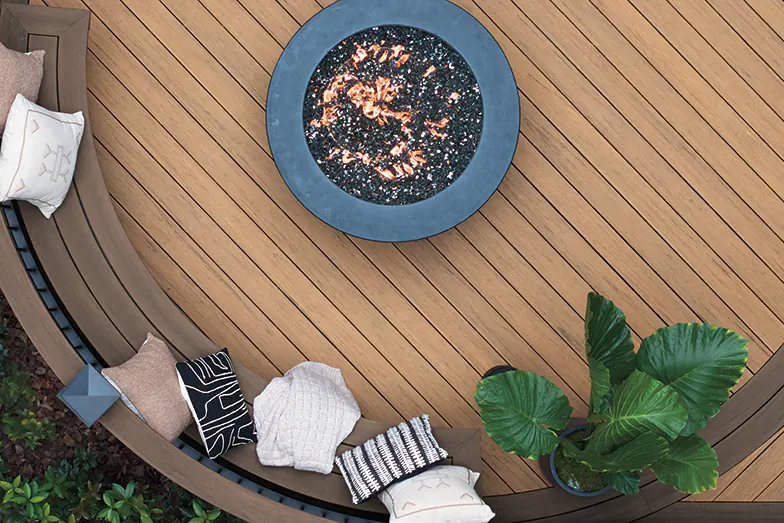 Aerial shot of a curved brown deck with reddish hues and an outdoor fire pit