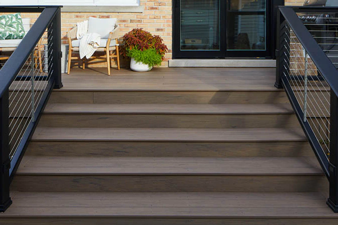 Stairs with sturdy black metal railing lead to the backdoor of a house with a brick facade