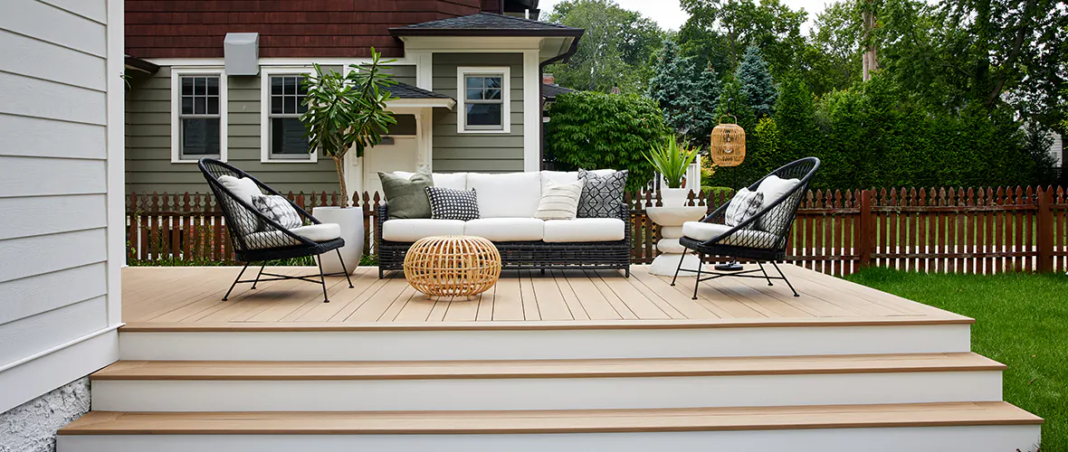 Simple, light tan deck with an outdoor seating area and two stairs leading up to the deck