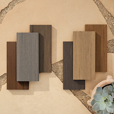 Six decking samples laid on the ground on smooth tan tiles.
