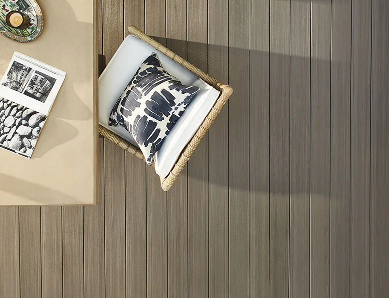 Sunlight illuminates the edges of a table and wicker chair in an aerial view of Mary Kate's TimberTech deck in Coastline
