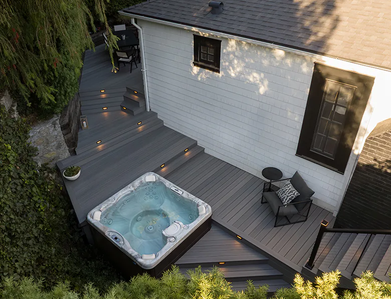 Aerial view of Tony's deck with a hot tub and riser lights that softly glow at sunset.