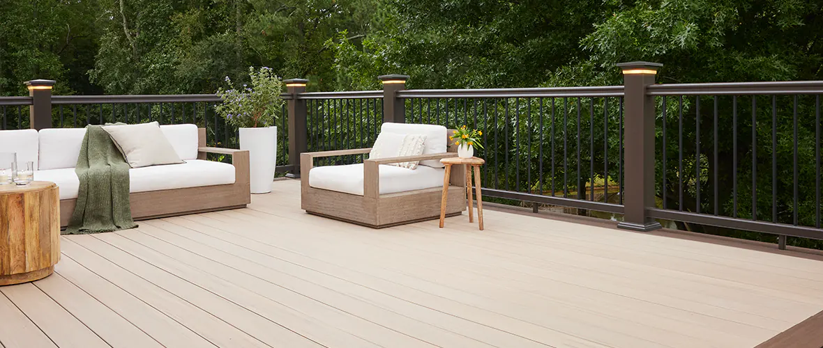 Light tan composite deck with integrated post cap lights on the railing that surrounds it.