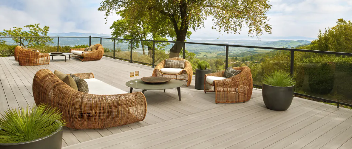 A second story TimberTech deck with a glass railing infill highlights the deck's proximity to nature.