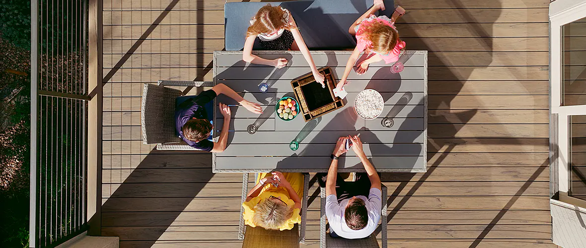 Aerial view of a family convening around an outdoor dining table to play board games together.
