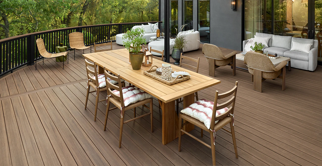 An outdoor dining room table and chairs introduce warm wooden tones complementing the rich brown hues of the deck boards below