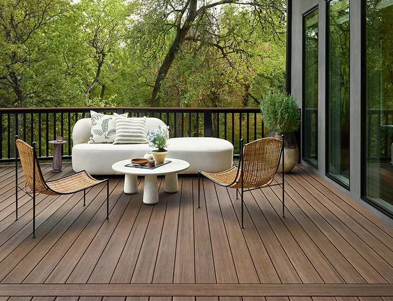 A modern, white couch and matching circular coffee table sits across from two wicker chairs on the deck